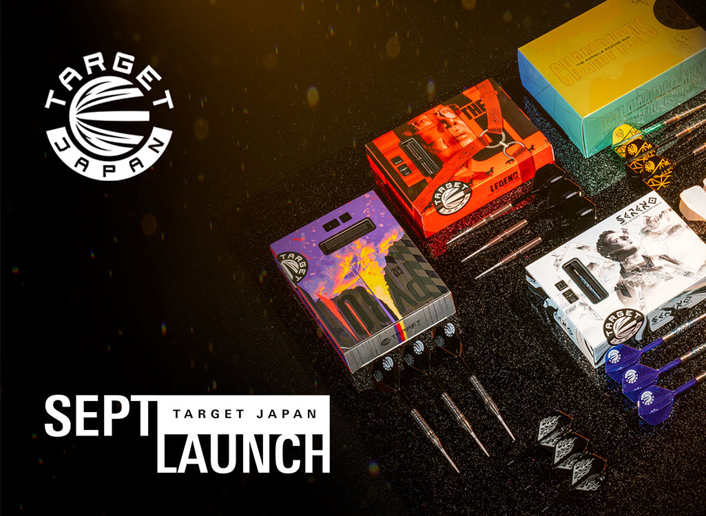 Target Japan Sept Launch promotional display featuring multiple dartboard accessories and boxes on a dark textured surface, including colorful retail boxes, metal darts, and blue dart flights, with Target Japan branding and 'SEPT LAUNCH' text.