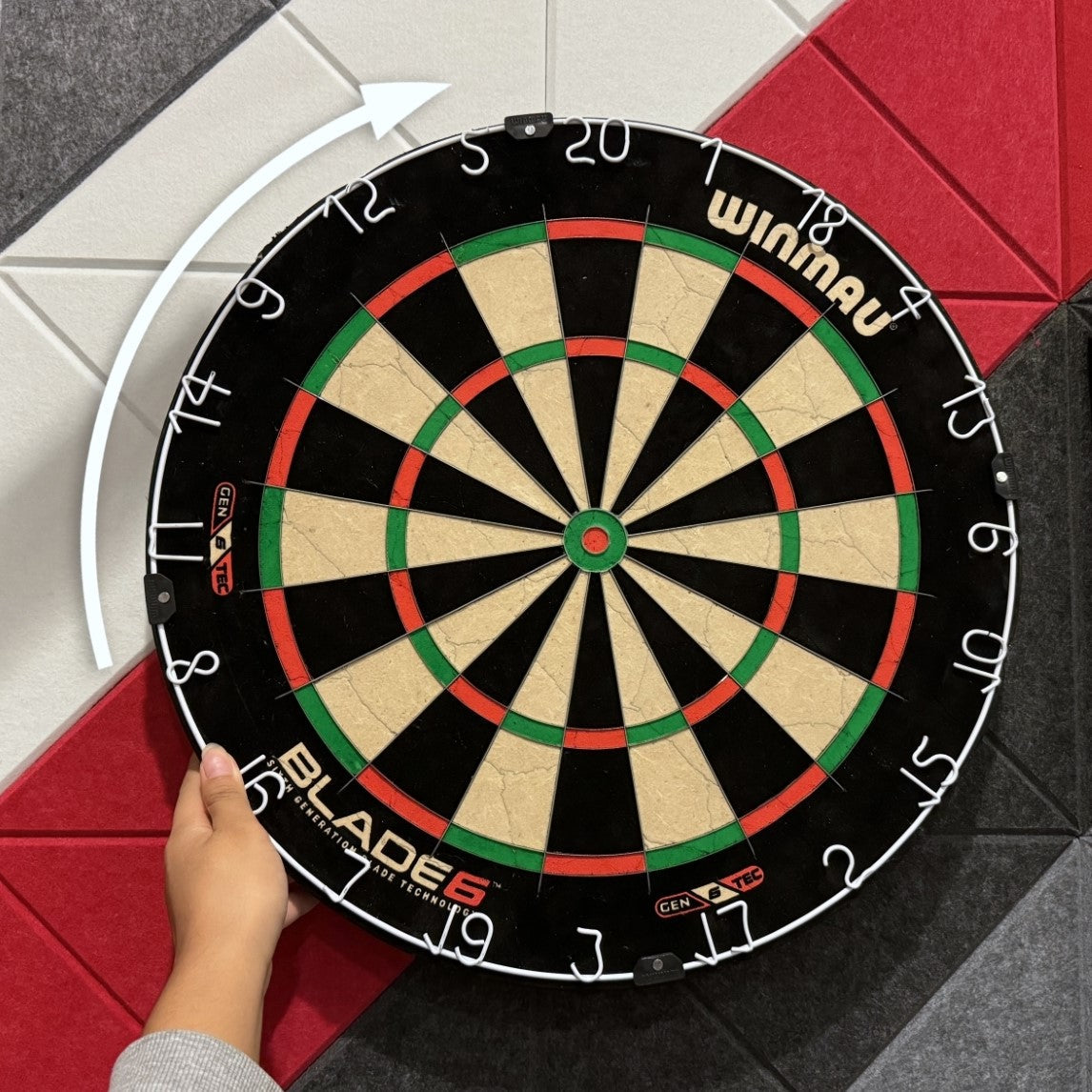 hand on steel tip dart board with curved arrow