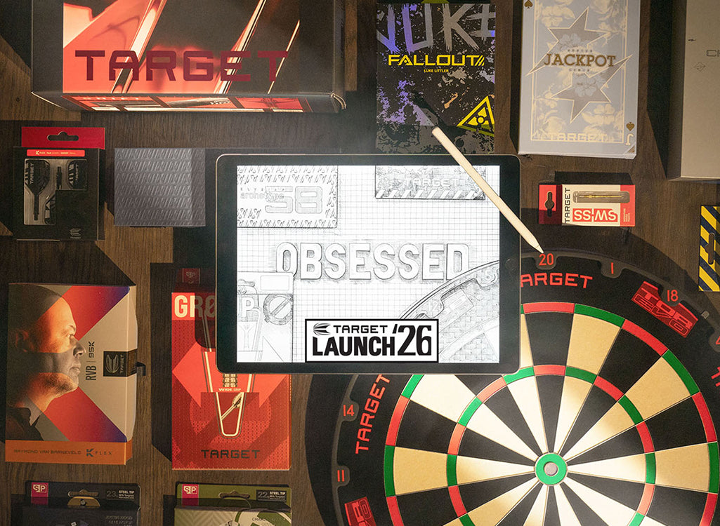 A promotional flat-lay for Target Launch 26 featuring a tablet in the center displaying the event logo, surrounded by Target-branded merchandise including a dartboard, boxes, and cards on a wooden surface.